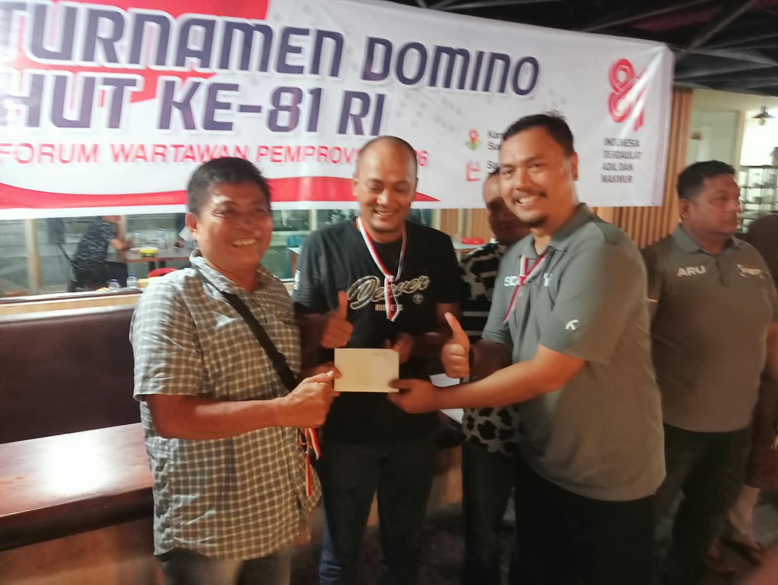 Ketua PWI Sumut Farianda Putra Sinik menyerahkan piala juara 1 kepada pasangan Bambang Sri Kurniawan dan Dicki Sihotang pada penutupan turnamen Domino FWP Sumut HUT ke-81 RI, di Medan Sabtu 22 Agustus 2026 (Foto: Jogi/instrumentasi.com)